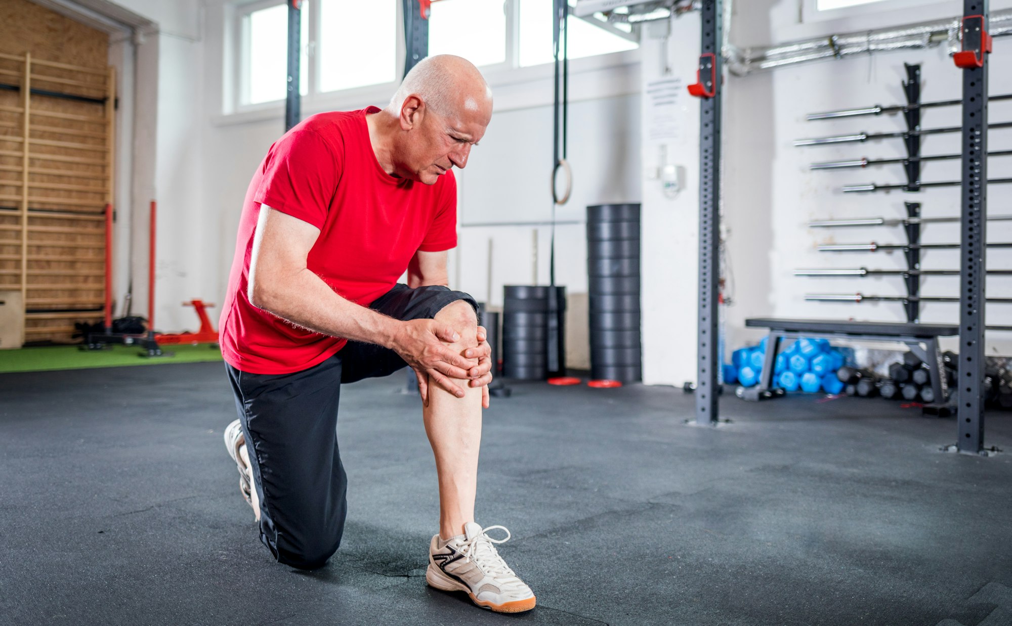 Senior man at the gym suffering from pain in knee